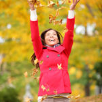 Happy fall woman throwing leaves