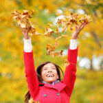 Happy fall woman throwing leaves